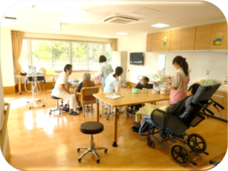 介護施設の共用スペースで入居者と職員が日中活動・レクリエーションを行っている風景