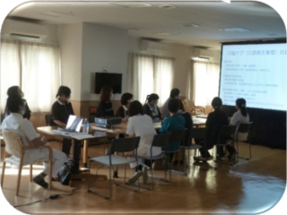 入居者と職員による講座またはレクリエーション活動の様子。スクリーンを使った学習・説明会。